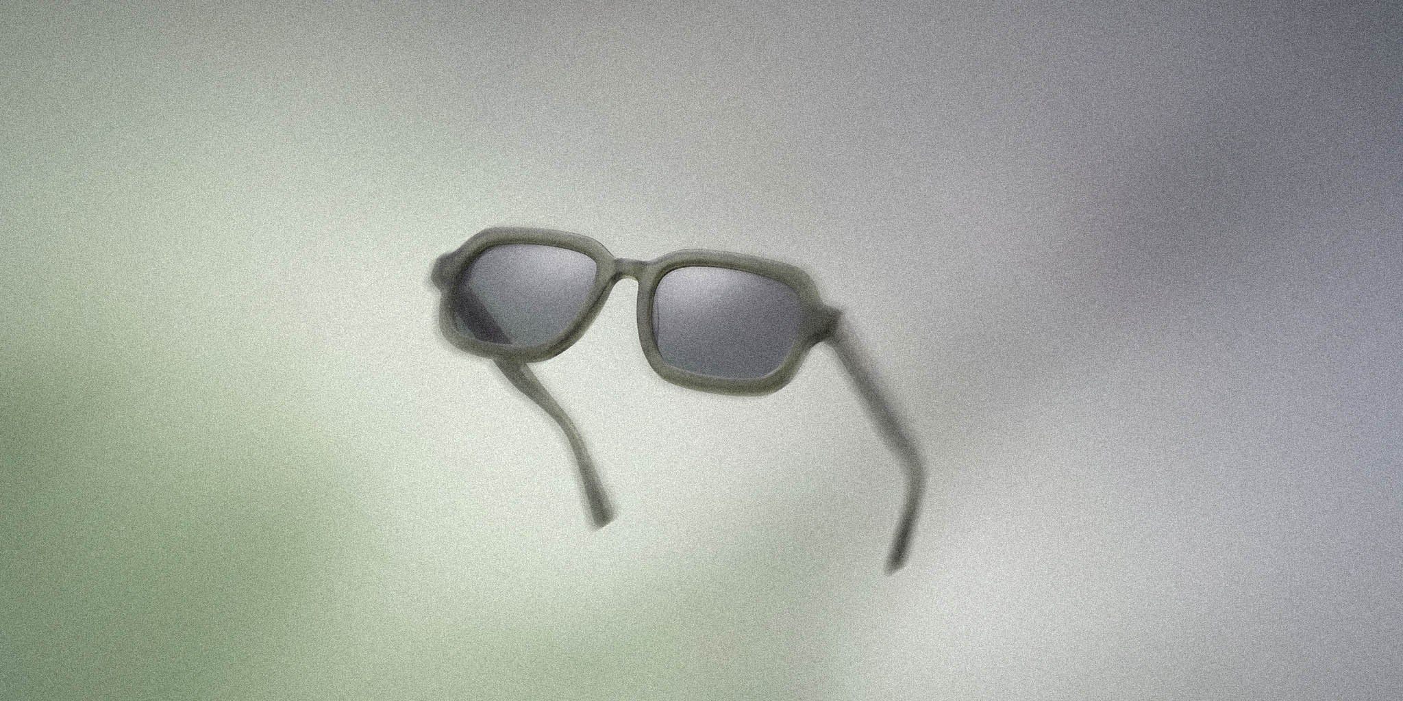 Matte gray rectangular sunglasses with dark lenses on a soft gradient background