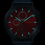 Red chronograph watch face with luminous blue hour markers and subdials in the dark