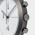 Close-up of a modern chronograph watch with white dial and metal pushers