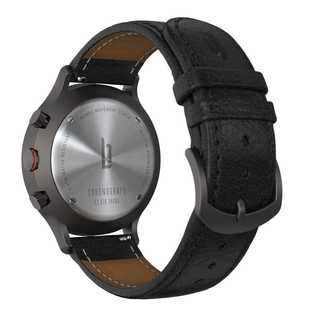 Close-up of a chronograph watch caseback with black leather strap and stainless steel details