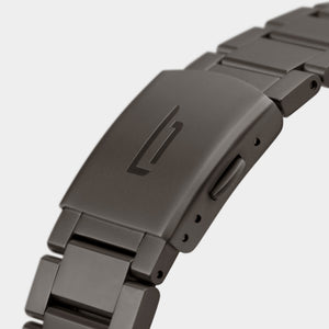 Close-up of matte metal watch bracelet clasp with engraved minimalist logo