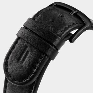 Close-up of a black leather watch strap with matte black buckle and stitched edges