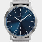 Minimalist steel watch with blue sunray dial, silver mesh strap, and date display