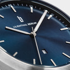 Close-up of a modern watch with a blue sunray dial, silver hands, and date display
