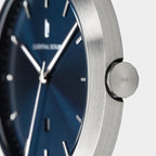 Close-up of minimalist wristwatch with brushed stainless steel case and blue dial
