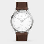 Minimalist silver wristwatch with white dial and brown leather strap on light background