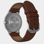 Stainless steel watch case back with brown leather strap and engraved details