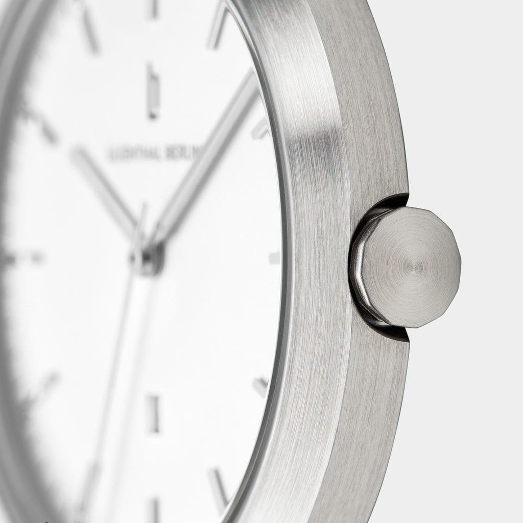 Close-up of minimalist silver watch with brushed metal case and white dial