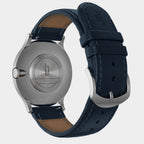 Stainless steel watch case back with blue leather strap, showcasing engraved details.