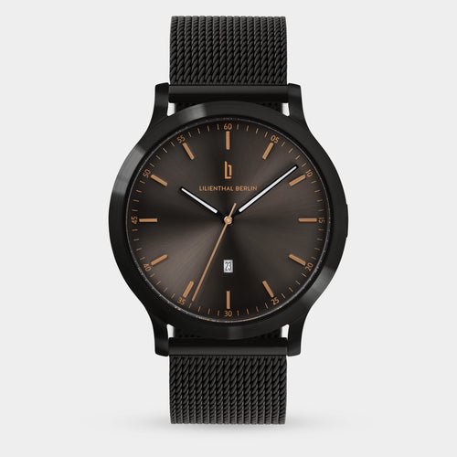 Minimalist black mesh strap watch with a dark sunburst dial and gold hour markers