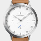 Minimalist silver watch with white dial, tan leather strap, and modern numeric markers.