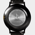 Close-up of stainless steel watch case back with engraved details and black strap