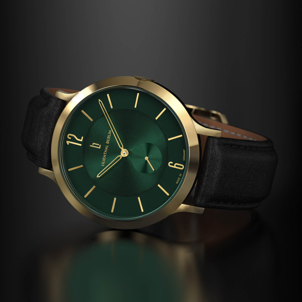 Gold-rimmed green dial watch with black leather strap on a dark background
