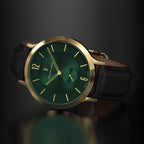 Gold-rimmed green dial watch with black leather strap on a dark background