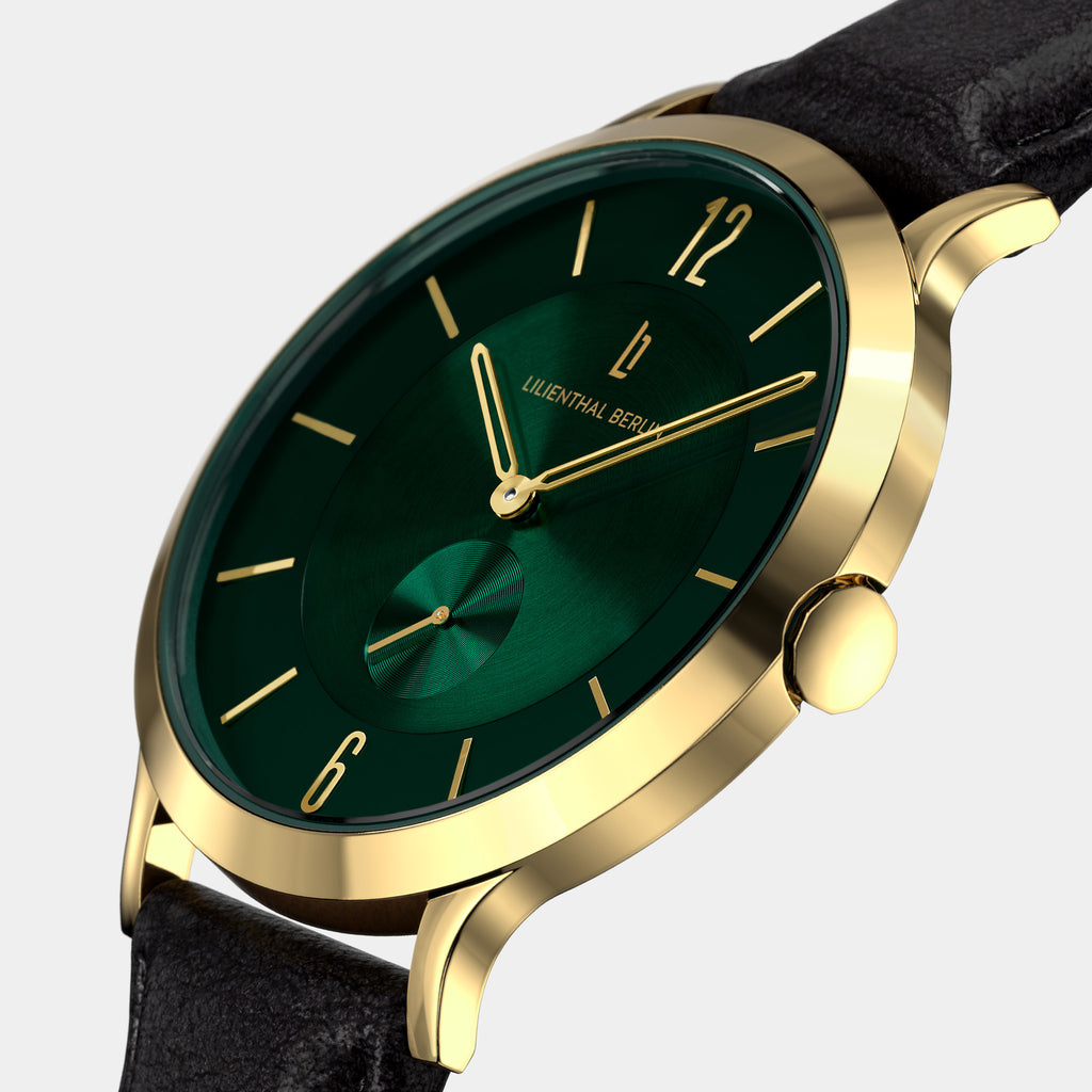 Gold wristwatch with green dial, gold markers, black leather strap, and minimalist design.