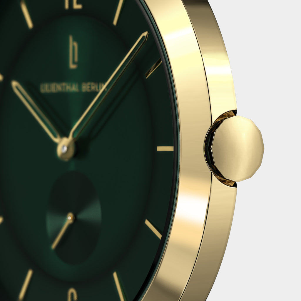 Close-up of elegant gold watch case with green dial and gold hour markers